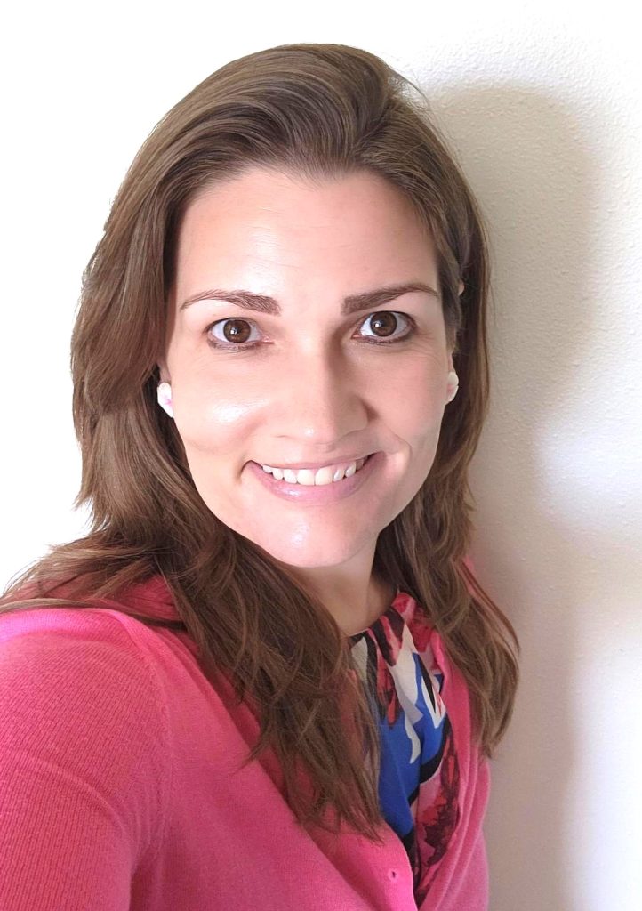 Photo of Dr. Laura Hetrick wearing a pink top. She has long brown hair and is smiling.