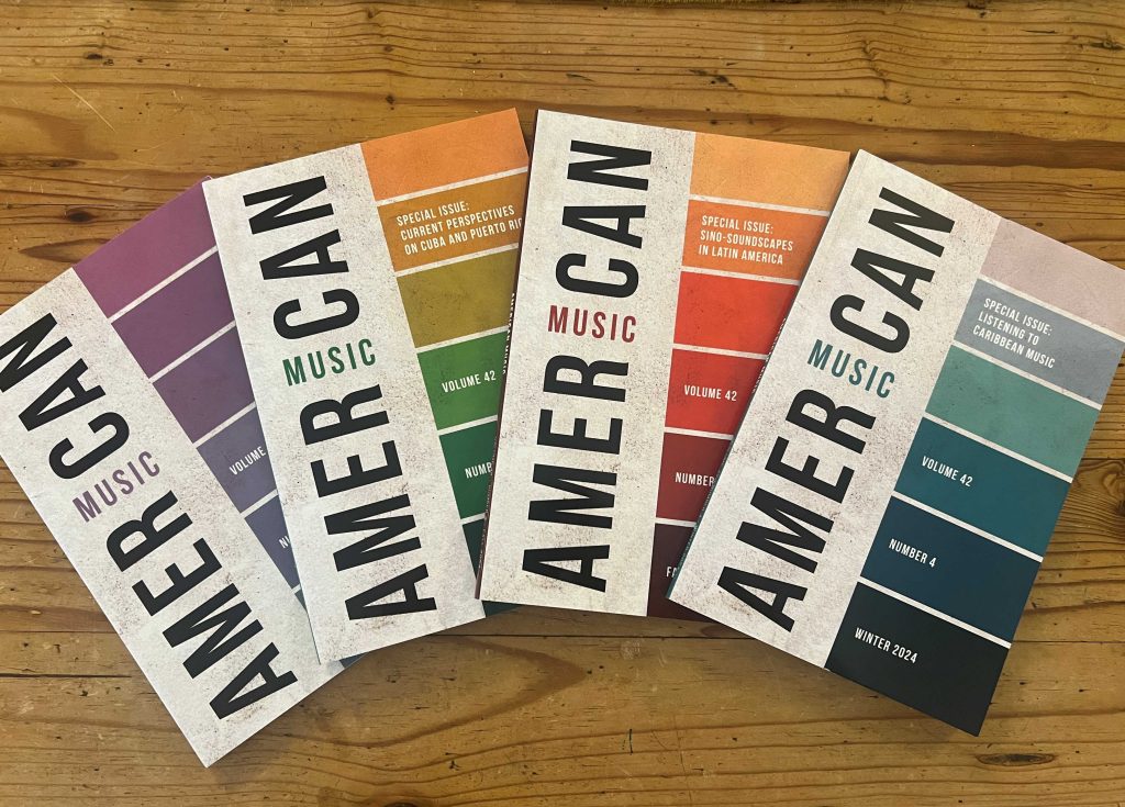 Four issues of American Music (Vol. 42) spread out on a wood background. Featuring American Music, Volume 42, Issue 4. Horizontal rectangles in a column on the right side of the cover in a gradient of teal and blue shades on white textured background.