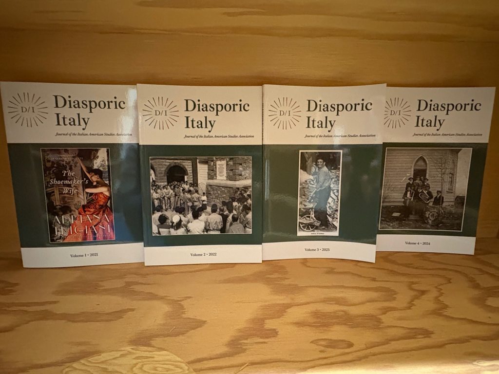 Four issues of Diasporic Italy lined up on a wooden shelf.