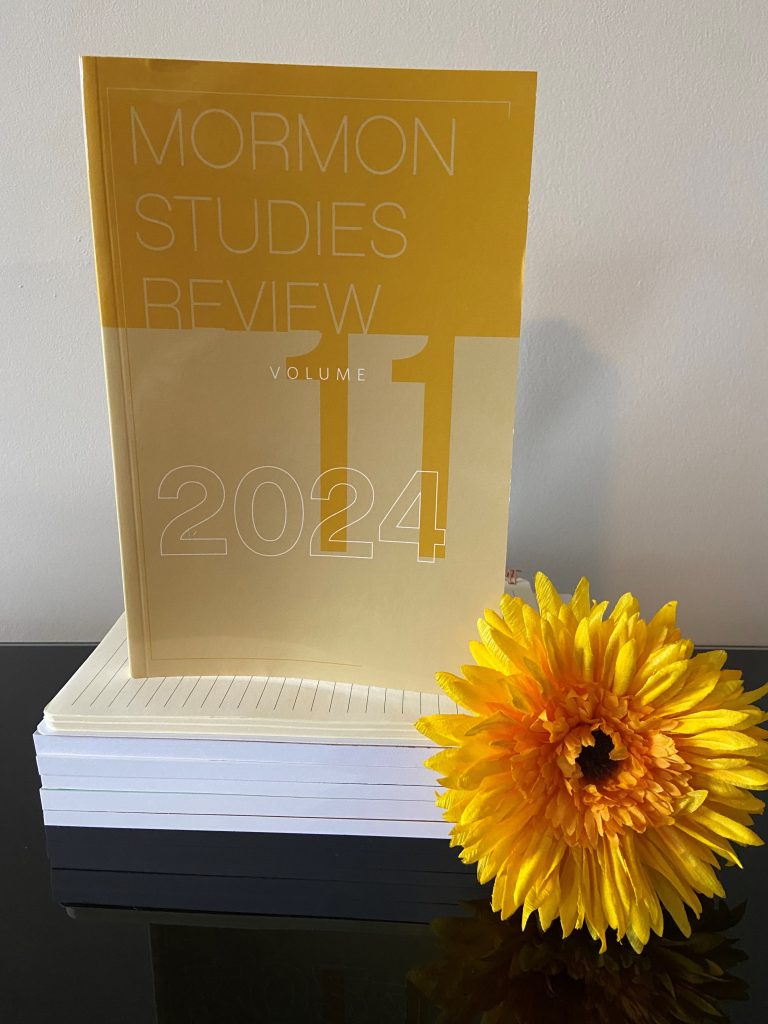 Copy of Mormon Studies Review standing next to yellow flower
