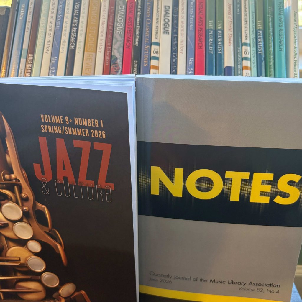 Two journal issues (Jazz & Culture and Notes) in front of a background showing spines of many other journals.